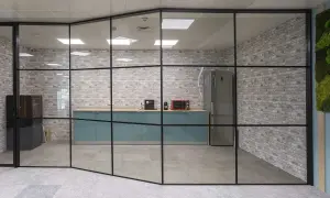 Una moderna cocina de oficina con una pared de cristal, gabinetes turquesas, electrodomésticos y una pared de ladrillos.