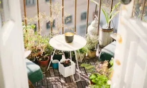 Ideas para aprovechar balcones pequeños: un rincón acogedor con plantas, mesa y silla, creando un oasis verde.