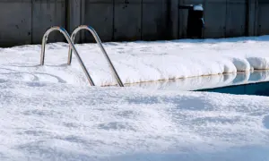 Escaleras de piscina asoman entre la nieve. Un reto para mantener piscina en invierno sin tapar.