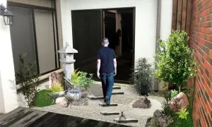 Un hombre camina hacia un sereno **patio jardín japonés en casa**, con una linterna de piedra y un estanque de bambú.