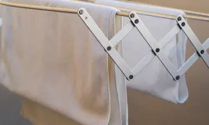 Tendedero metálico con toallas blancas colgadas, ideal para colocar tendedero en fachada de SATE.