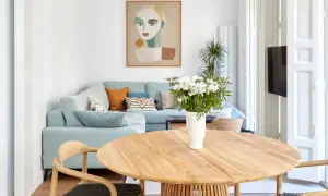 Elegante decoracion salon comedor con sofá azul claro, mesa de madera y cuadro abstracto.