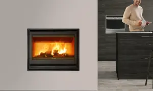 Chimenea cassette con fuego encendido. Un hombre sonríe con una taza y una tablet en una cocina moderna.