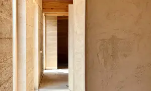 Pasillo con paredes de mortero de cal interiores, textura natural y vigas de madera en el techo.