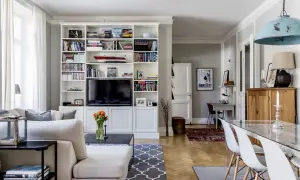 Ideas para cómo distribuir un salón comedor cuadrado: zona de estar con sofá y estanterías, y zona de comedor con mesa de cristal.