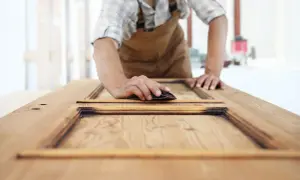Carpintero lijando una puerta de sapelly para modernizarla.