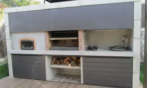 Cocina exterior con parrilla, horno de leña, bacha y anafe. Un ejemplo de quinchos modernos, ideal para disfrutar al aire libre.
