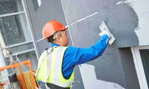 Obrero aplica revestimiento a un panel aislante térmico exterior.