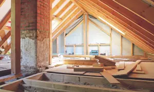 El **altillo de madera** está en construcción, con vigas expuestas y materiales de construcción esparcidos.