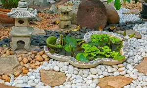 Un sereno jardín zen japonés con un estanque de lotos, linternas de piedra y rocas de diferentes tamaños.
