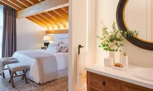 Habitación con vigas de madera y baño con espejo redondo. ¿Cuanto mide una habitación normal? Esta parece espaciosa.