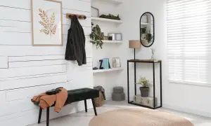 Entrada moderna con banco verde, perchero, consola y espejo ovalado.