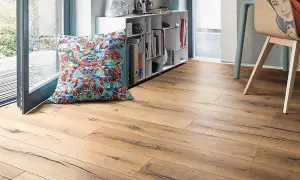 Suelo laminado de madera con un cojín colorido y estantería. Ideal para aprender como poner suelo laminado.