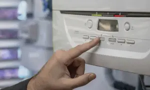 Mano ajustando el control de una caldera, quizás para solucionar porque se baja la presion de la caldera.