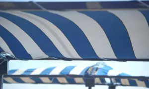 Toldo a rayas azules y blancas, listo para cambiar la tela y proteger del sol.