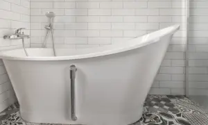 Baño moderno con bañera blanca y grifería cromada. El suelo tiene baldosas hidráulicas. Ideal para reparar bañera picada.
