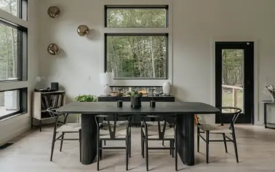 Mesa de comedor moderna con sillas de madera y asientos de mimbre. Un jarrón blanco y dos candelabros negros decoran la mesa, perfecta para decorar mesa comedor.