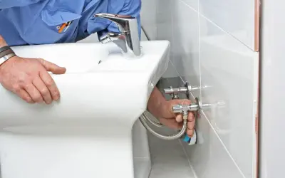 Fontanero desconectando mangueras de un bidet. Guía para como quitar un bidet paso a paso.