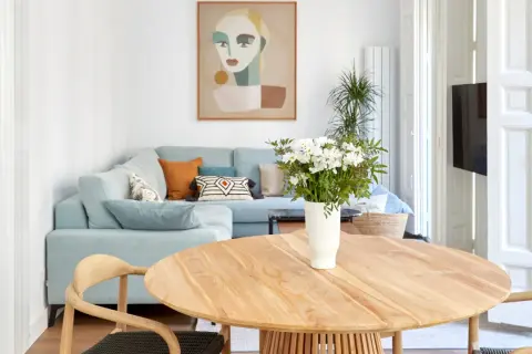 Elegante decoracion salon comedor con sofá azul claro, mesa de madera y cuadro abstracto.
