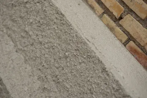 Textura rugosa de un muro de ladrillos y cemento. El acrílico que es este material de construcción, se ve en primer plano.