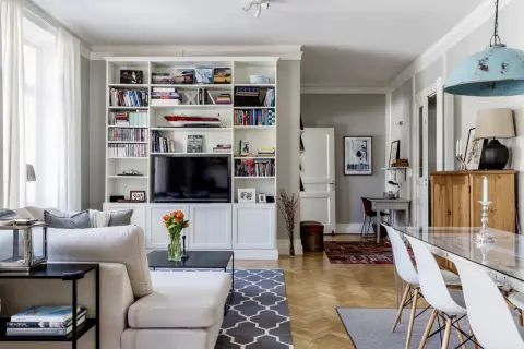 Ideas para cómo distribuir un salón comedor cuadrado: zona de estar con sofá y estanterías, y zona de comedor con mesa de cristal.