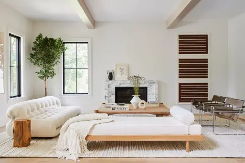 Elegante salón combinar madera y blanco. Sofá blanco texturizado, diván de madera, chimenea de mármol y sillones modernos.