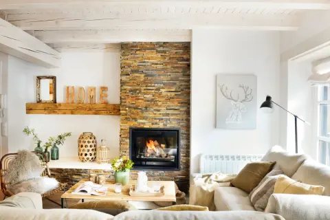 Acogedor salón nórdico rústico con chimenea de piedra, vigas de madera y decoración natural.