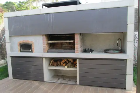 Cocina exterior con parrilla, horno de leña, bacha y anafe. Un ejemplo de quinchos modernos, ideal para disfrutar al aire libre.
