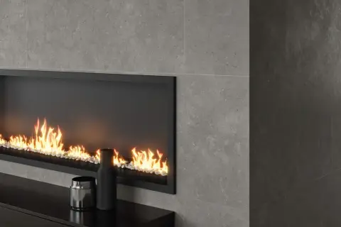 Chimenea moderna con revestimiento de piedra gris y fuego acogedor.