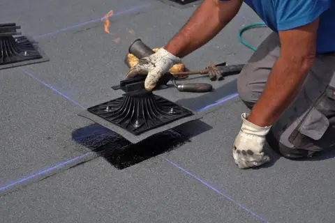 Instalador aplica calor con soplete para sellar la tela asfáltica, asegurando una impermeabilización perfecta.
