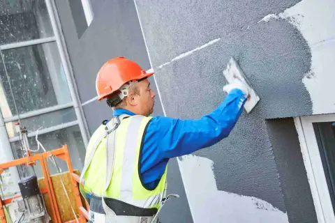 Obrero aplica revestimiento a un panel aislante térmico exterior.