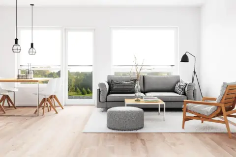 Elegante salón comedor con sofá gris, mesa de centro y sillas blancas. La iluminación moderna ayuda a combinar lamparas salon comedor.