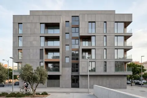 Edificio moderno con una elegante fachada ventilada de paneles grises, balcones acristalados y detalles en madera. Un ciclista pasa frente a árboles y la calle.