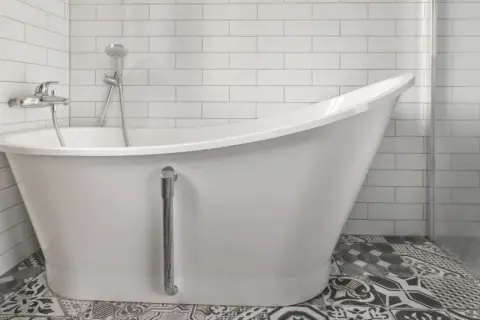 Baño moderno con bañera blanca y grifería cromada. El suelo tiene baldosas hidráulicas. Ideal para reparar bañera picada.