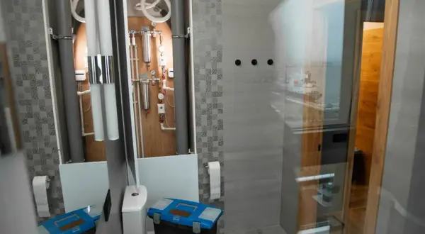 Herramientas listas para instalar mampara ducha esquina. Baño moderno con tuberías visibles y vista al mar.