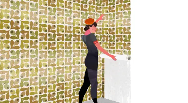 Una mujer con boina naranja y vestido gris está aprendiendo cómo empapelar una pared con un patrón de hojas y olivas.
