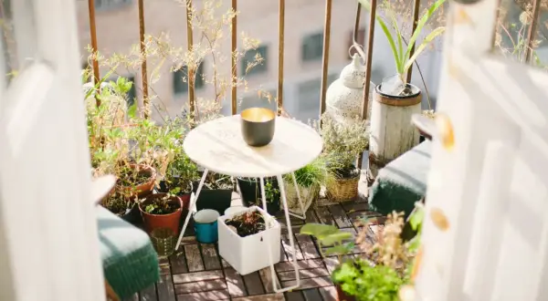 Ideas para aprovechar balcones pequeños: un rincón acogedor con plantas, mesa y silla, creando un oasis verde.