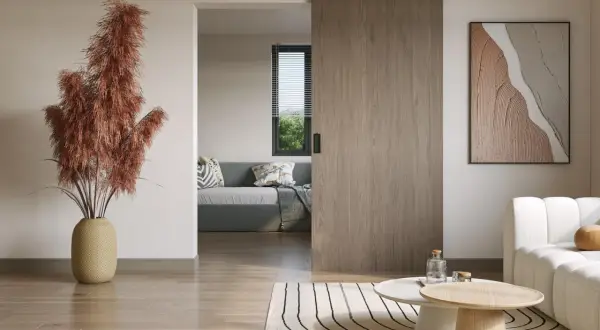 Instalar puerta corredera de madera en un salón moderno. Un jarrón con pampas secas y un cuadro abstracto decoran el espacio.