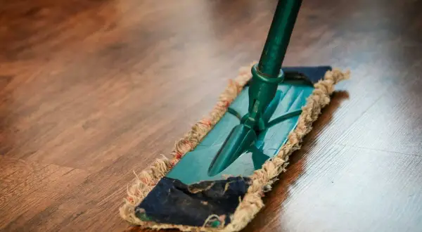 Mopa sobre suelo de madera. Descubre remedios caseros para reparar parquet y mantenerlo como nuevo.