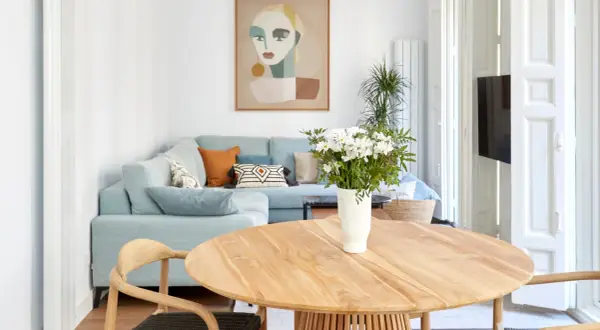 Elegante decoracion salon comedor con sofá azul claro, mesa de madera y cuadro abstracto.