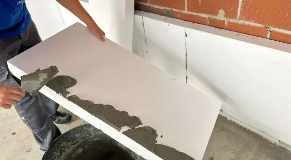 Aplicando mortero sobre poliestireno extruido para aislamiento.