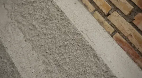 Textura rugosa de un muro de ladrillos y cemento. El acrílico que es este material de construcción, se ve en primer plano.