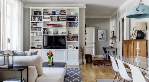 Ideas para cómo distribuir un salón comedor cuadrado: zona de estar con sofá y estanterías, y zona de comedor con mesa de cristal.