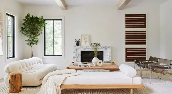 Elegante salón combinar madera y blanco. Sofá blanco texturizado, diván de madera, chimenea de mármol y sillones modernos.