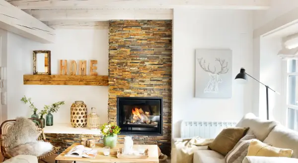 Acogedor salón nórdico rústico con chimenea de piedra, vigas de madera y decoración natural.