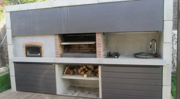 Cocina exterior con parrilla, horno de leña, bacha y anafe. Un ejemplo de quinchos modernos, ideal para disfrutar al aire libre.