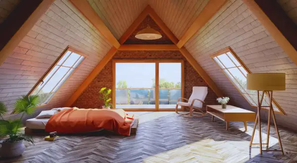 Acogedor dormitorio abuhardillado con cama naranja, mecedora y grandes ventanales. Ideal para **aprovechar buhardilla muy baja** con estilo y luz.