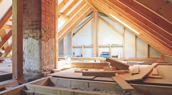 El **altillo de madera** está en construcción, con vigas expuestas y materiales de construcción esparcidos.