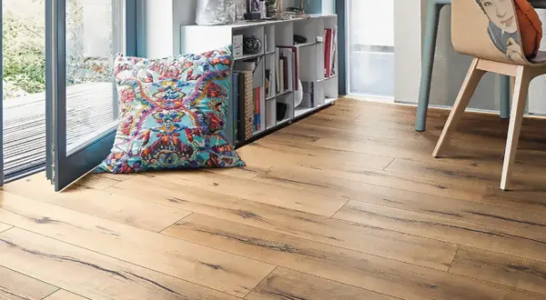 Suelo laminado de madera con un cojín colorido y estantería. Ideal para aprender como poner suelo laminado.