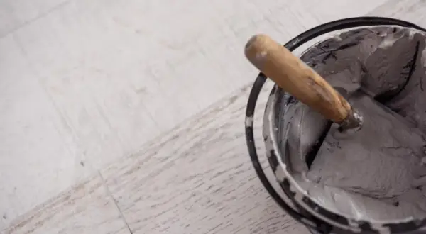 Paleta con morteros de revestimiento listos para aplicar sobre suelo de madera.